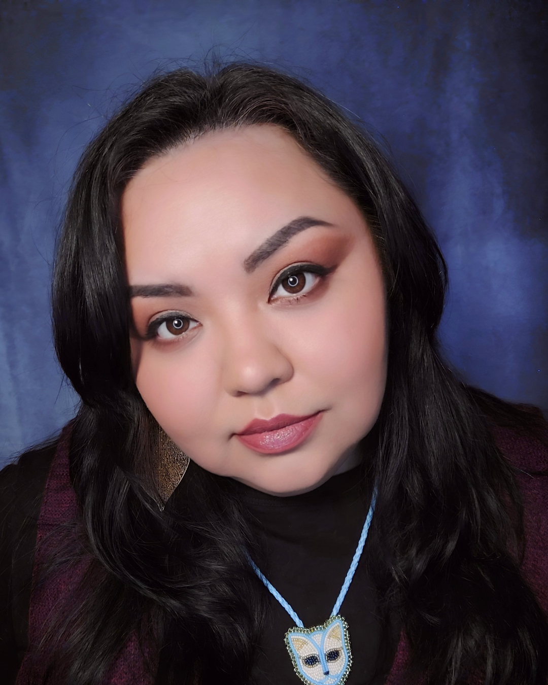 Headshot of Johnnie Jae in a black top in front a blue backdrop
