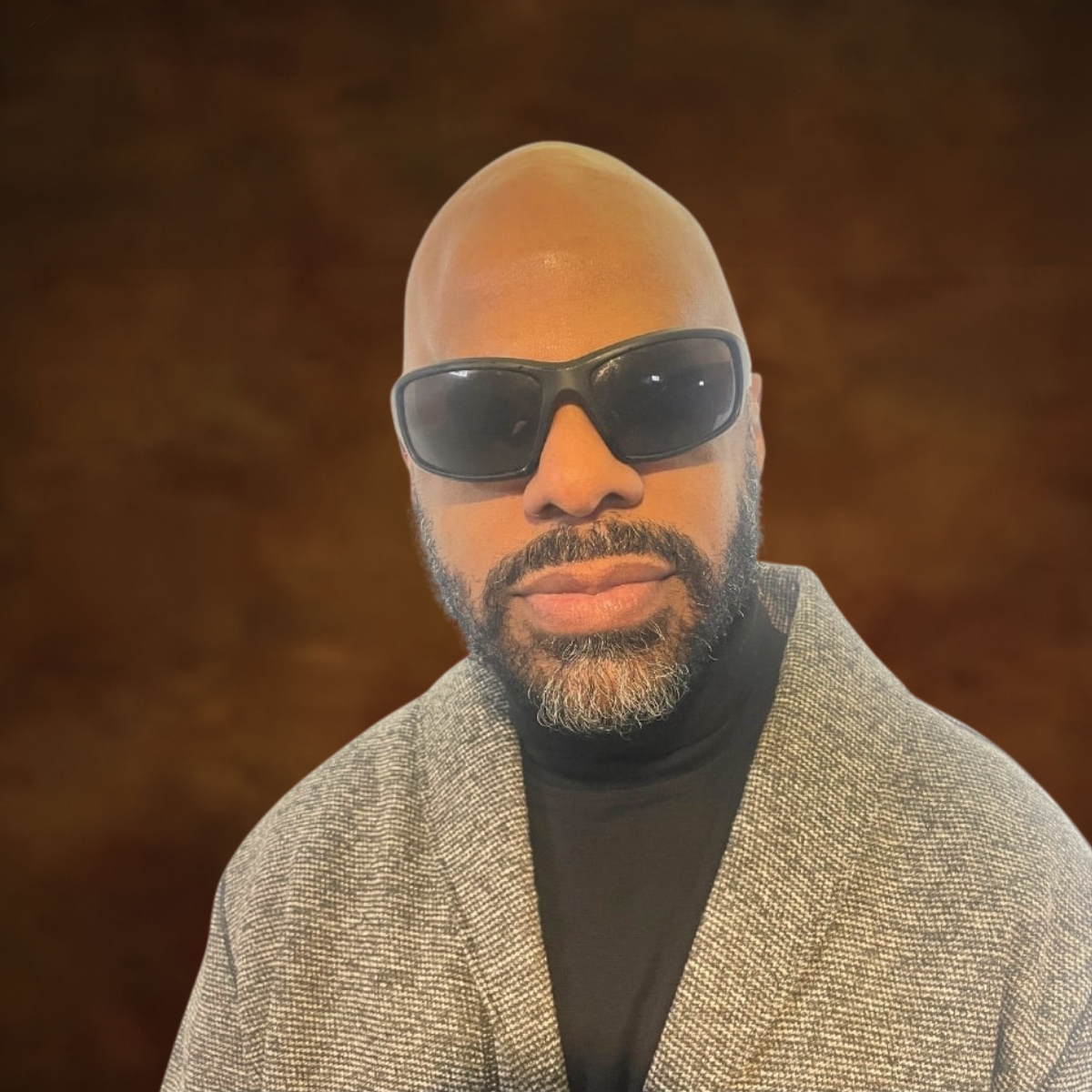 Photo of Thomas Reid wearing sunglasses in front of a brown backdrop
