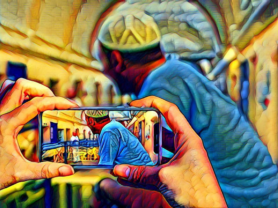 Image of hands holding a cell phone taking a photo of a man's side profile