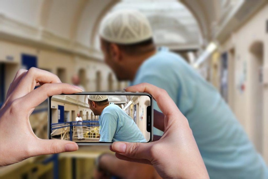 Image of hands holding a cell phone taking a photo of a man's side profile